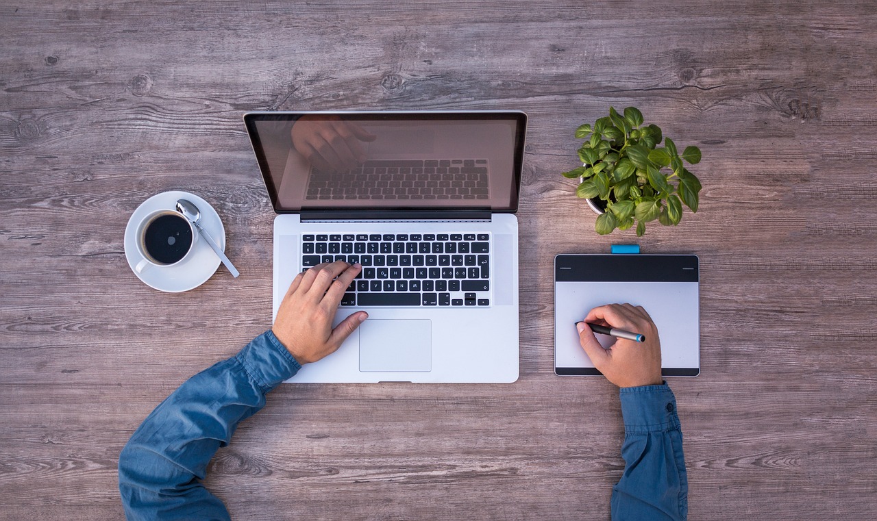 Visão de computador, chávena com café, vaso de flores e pessoa a escrever