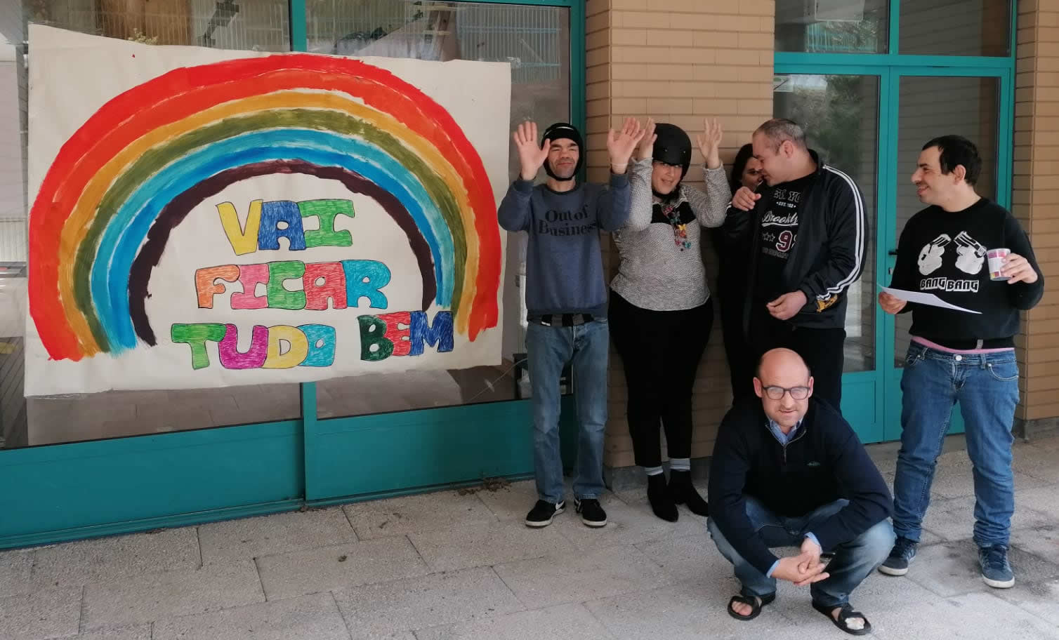 Seis clientes do lar residencial da Cercigui com a faixa "Vai ficar tudo bem" e o arco-íris pintado